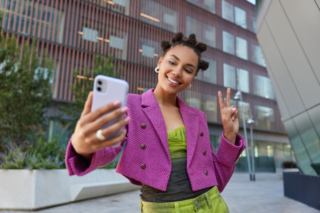 garota-atraente-com-roupa-elegante-cria-conteudo-de-influencia-mostra-o-simbolo-da-paz-em-poses-de-camera-frontal-do-smartphone-para-sorrisos-de-selfie